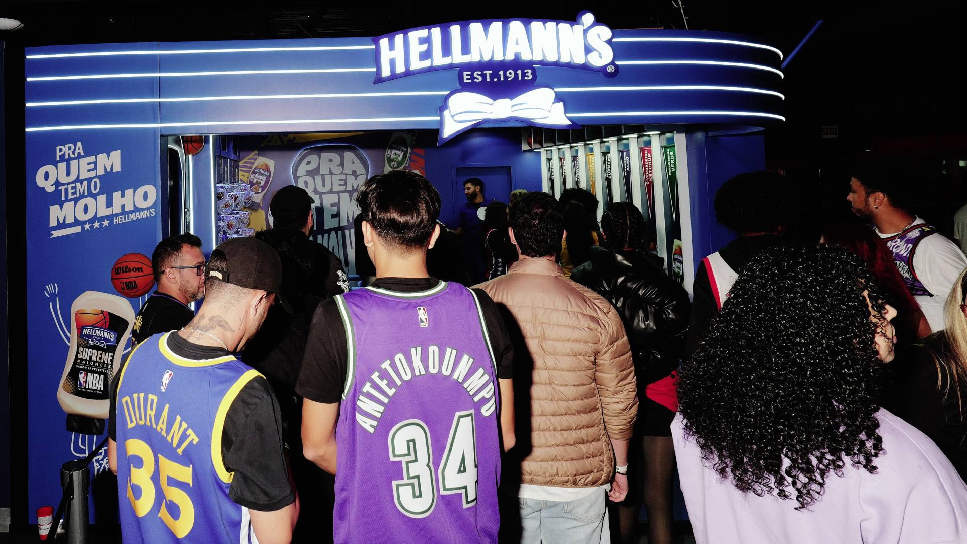 Um grupo de jovens fãs de basquete vestindo camisetas de times da NBA entra em um evento patrocinado pela Hellmann's