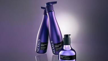 Três frascos de produtos Nexxus Keraphix. Frascos lilás de shampoo e condicionador, e um frasco metálico menor com dosador preto.