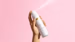Um desodorante Dove para todo o corpo, em spray, com fragrância de framboesa e rosa, sobre um fundo rosa claro.