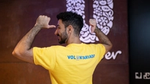 Homem de camiseta amarela escrita "voluntariado" nas costas.