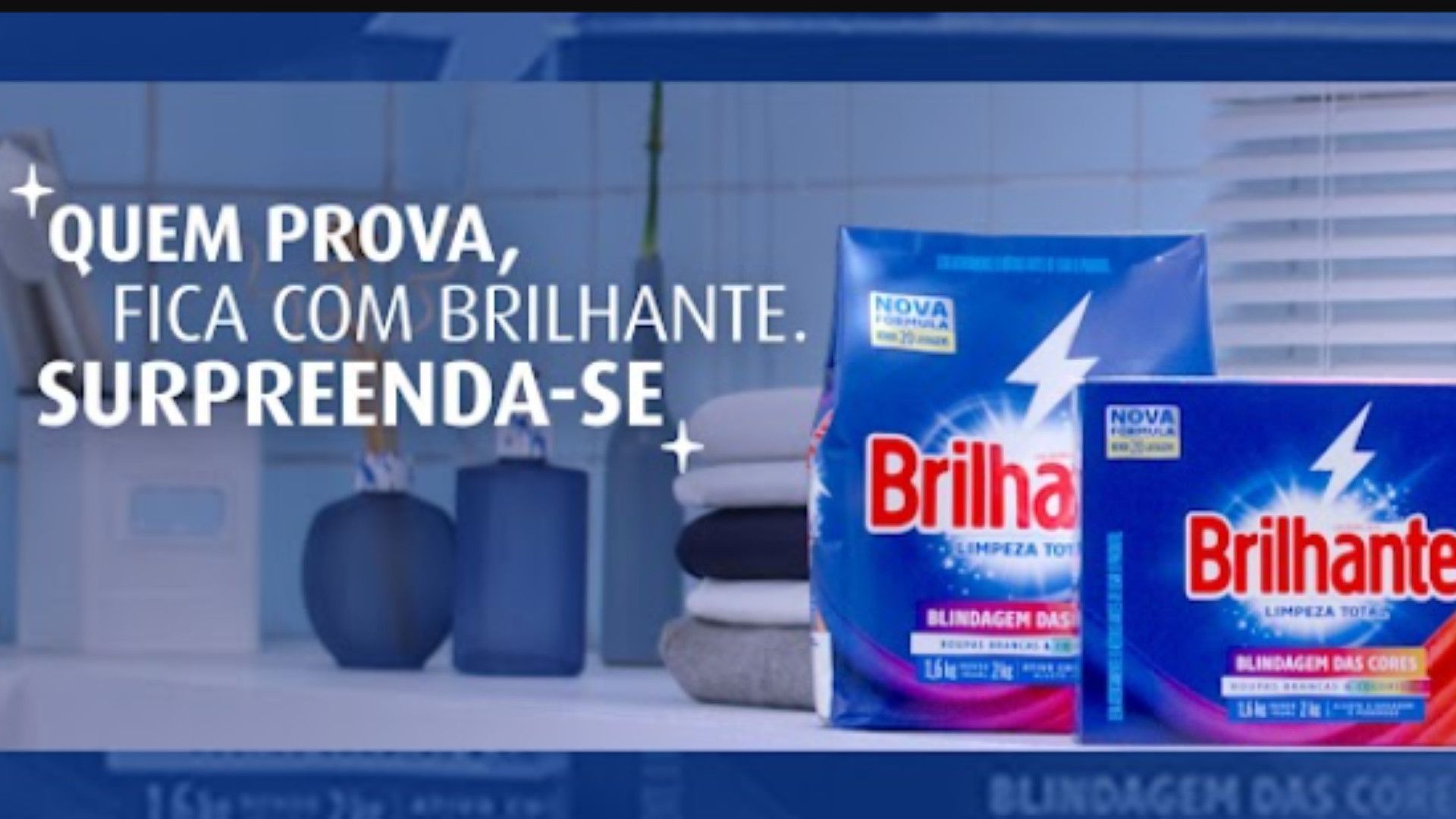 Duas embalagens do produto de limpeza Brilhante em destaque contra um fundo azul, com roupas dobradas e utensílios de limpeza.